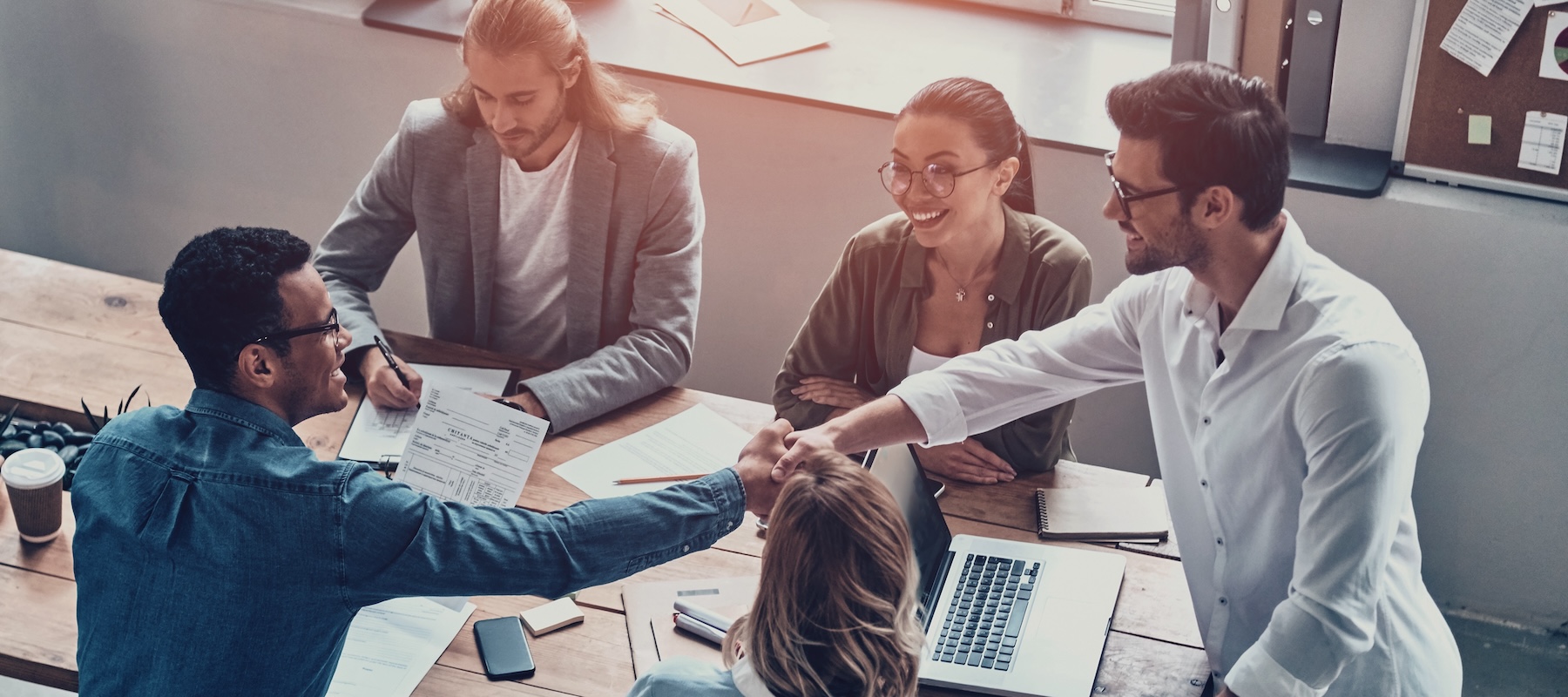 Image of a team at a table shaking hands